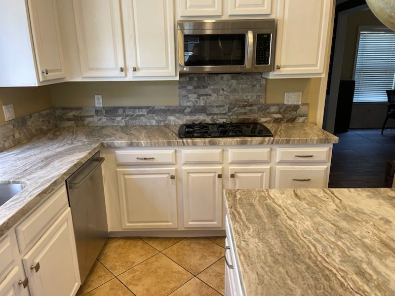A kitchen with white cabinets and a large island in the middle.