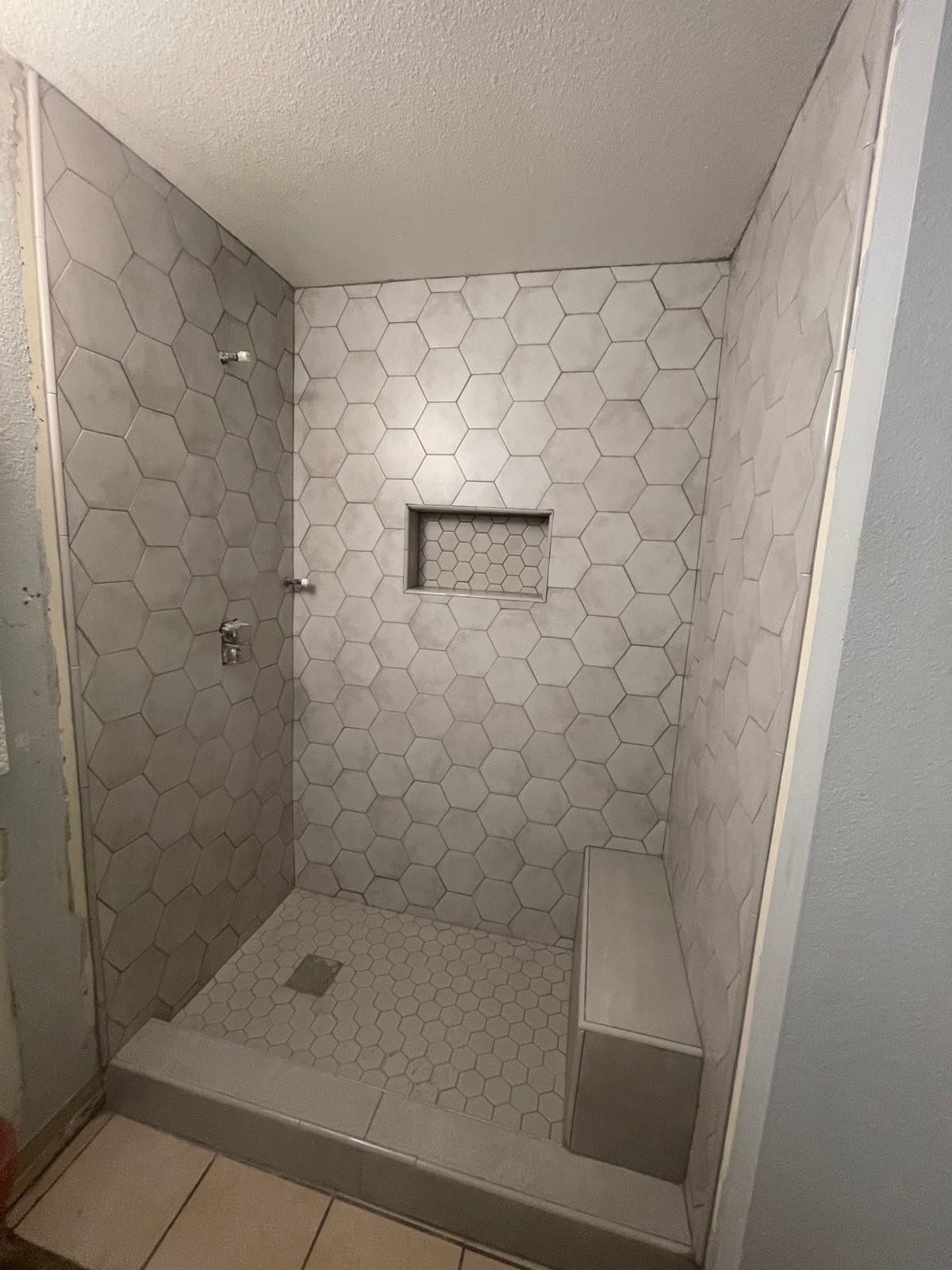 A bathroom with a walk in shower and a bench.