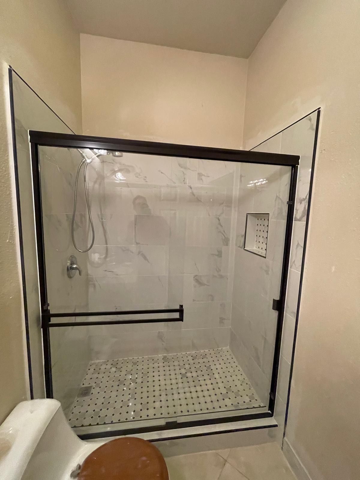 A bathroom with a sliding glass shower door and a toilet.