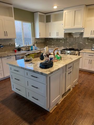 A kitchen with white cabinets and a large island in the middle.