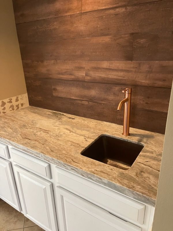 A kitchen counter with a sink and a copper faucet.