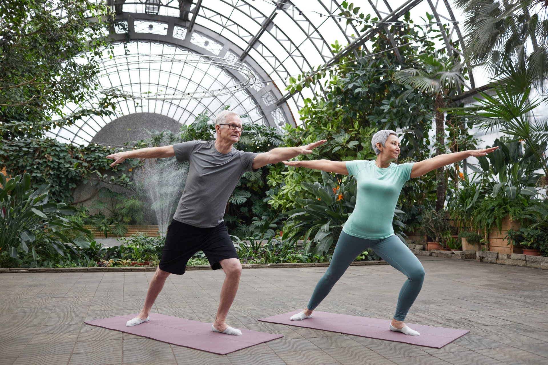 Couple practicing yoga together surrounded by trees