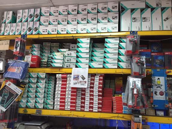 Shelves in a store stocked with various boxes and packaged tools, mostly white, teal, and red.