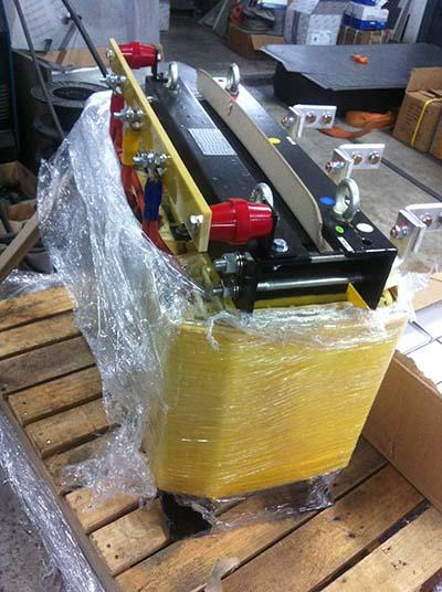 Yellow and black industrial equipment, wrapped in plastic, on a wooden pallet.