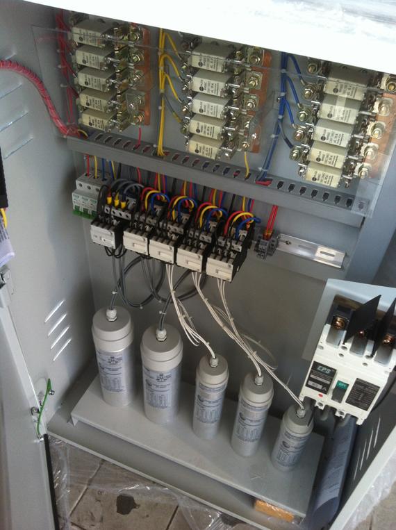 Electrical control panel with capacitors, relays, and wiring.