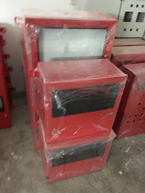 Red metal electrical boxes, stacked and wrapped in plastic, indoors.