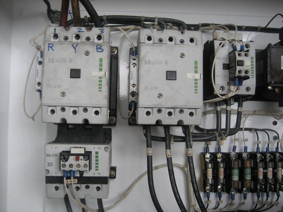 Electrical panel with several contactors and other components, connected by wires.