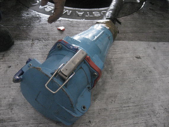Blue industrial connector on concrete next to a manhole.