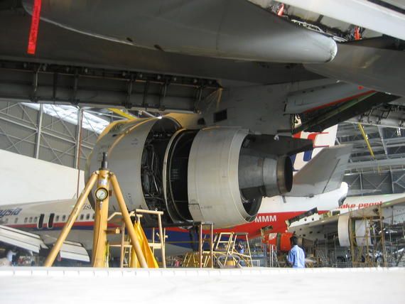 Airplane engine being serviced in a hangar. Blue, red, and white fuselage. Yellow support scaffolding.