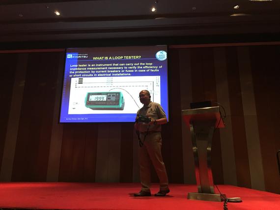 Man presenting on stage with a screen displaying a 