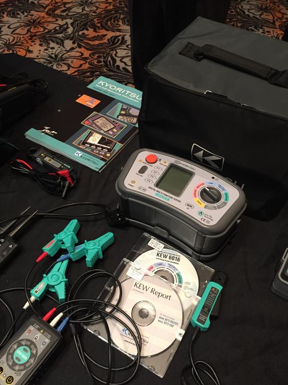 Electrical testing equipment with accessories on a table, including a digital multimeter and cables.