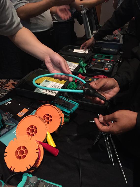 People examining electrical testing equipment laid out on a black table.