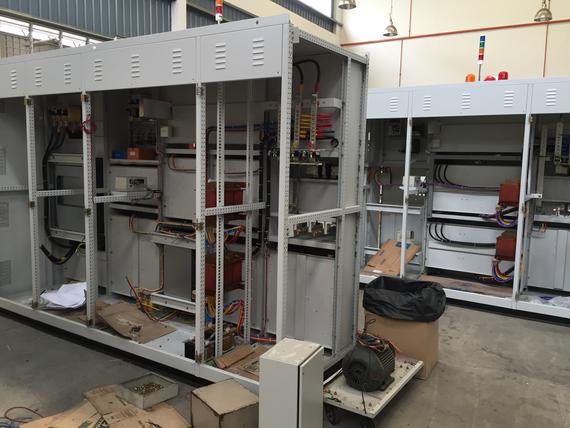 Electrical control panels with open doors, under construction, in an industrial setting.