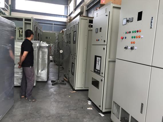 Man standing in a warehouse with electrical control panels, which are beige.