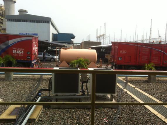 Industrial scene with red containers, air conditioning units, and a beige water tank.