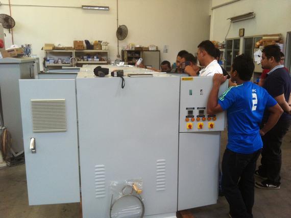 Group of people observing industrial machinery in a workshop.