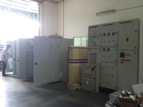 Electrical control panels inside a warehouse; a person stands nearby.