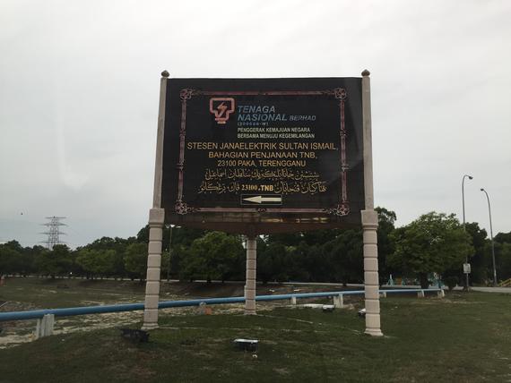 Sign for Tenaga Nasional Berhad in Malaysia. Dark sign with white lettering on a road.