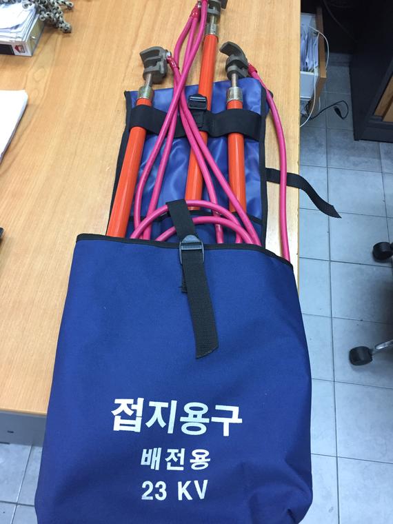 Blue bag with Korean text and red grounding sticks, likely for electrical work.