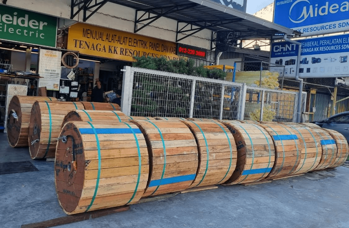 Wooden cable spools stacked outside a shop; signage for Schneider Electric, and Midea.