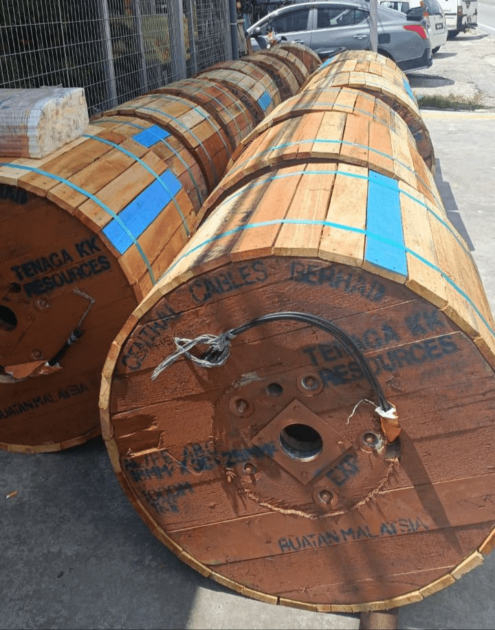 Wooden cable spools, stacked outdoors, labeled with 