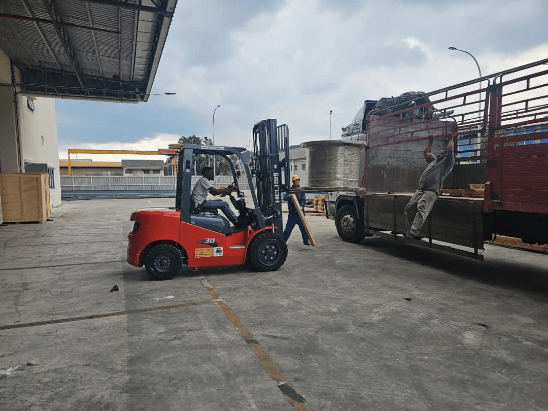 A red forklift and two men loading a truck in a warehouse setting.