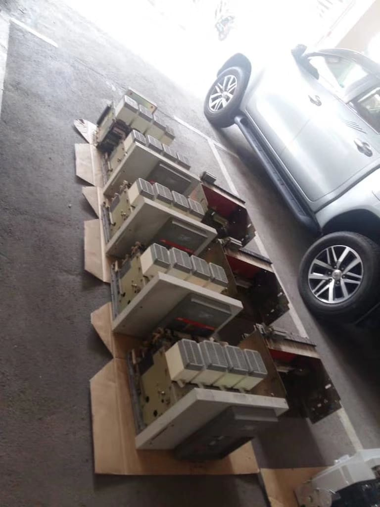 Line of industrial equipment on cardboard, next to a silver truck in a parking lot.
