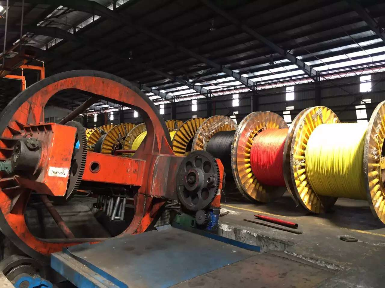 Factory with large machinery and spools of colorful electrical cables.