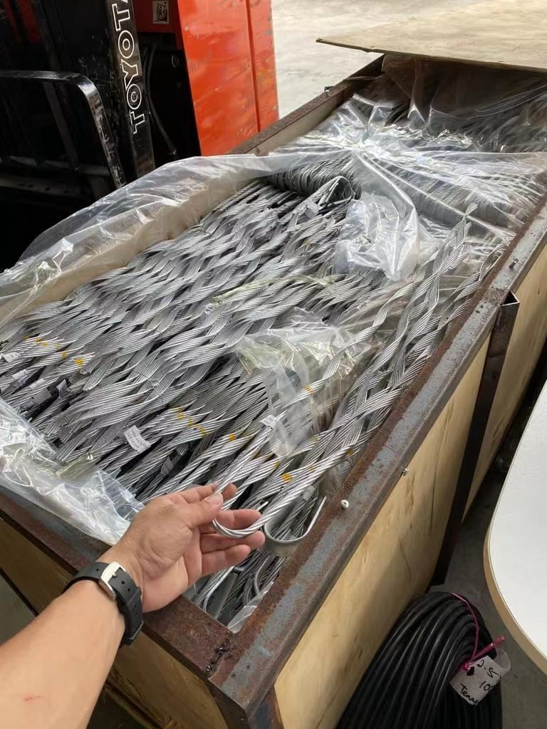 Person holding a metal hook from a crate full of metal rods, likely construction materials.