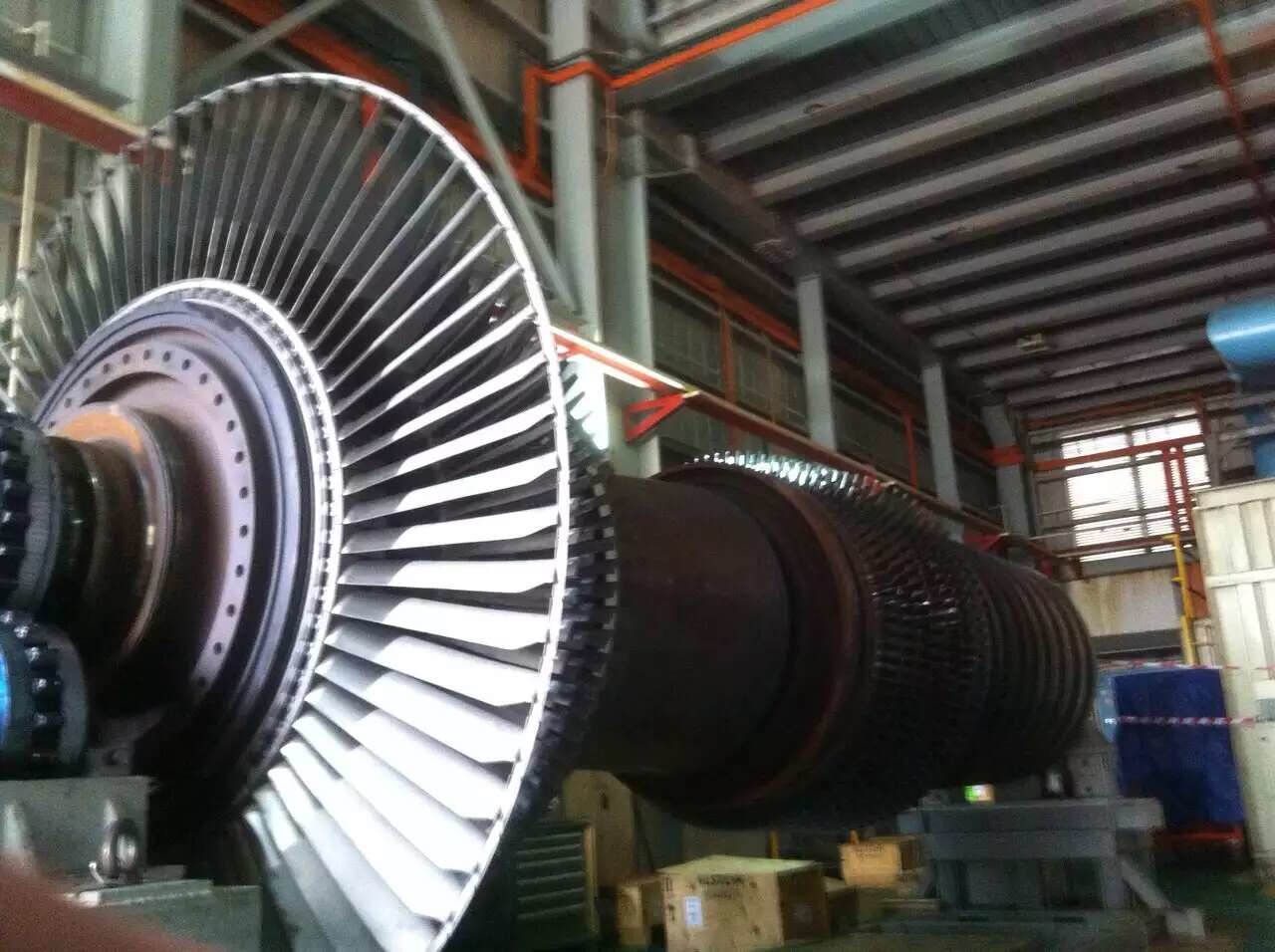 Large turbine rotor with blades in a factory setting.