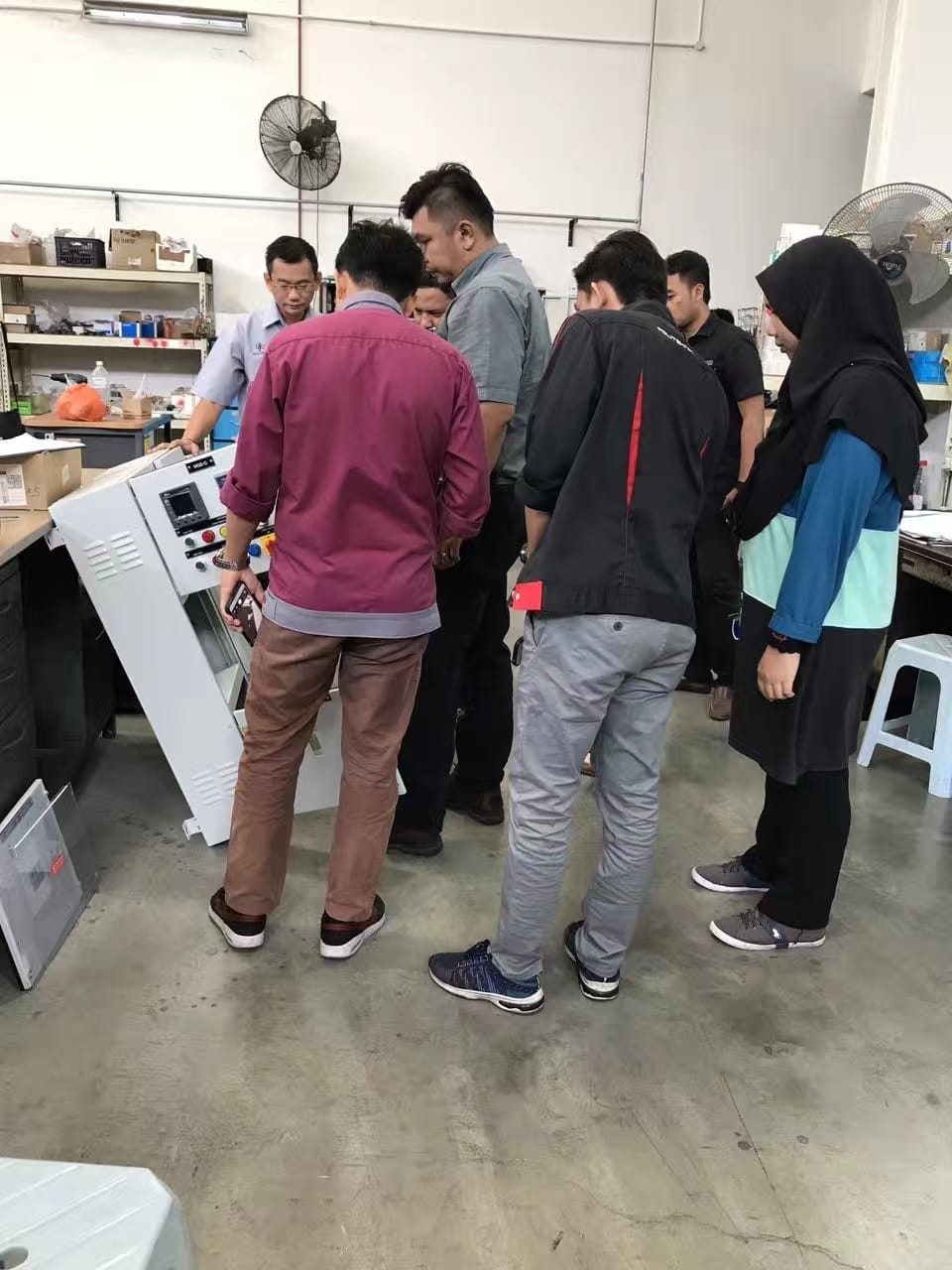 A group of people examining a panel in a workshop setting.