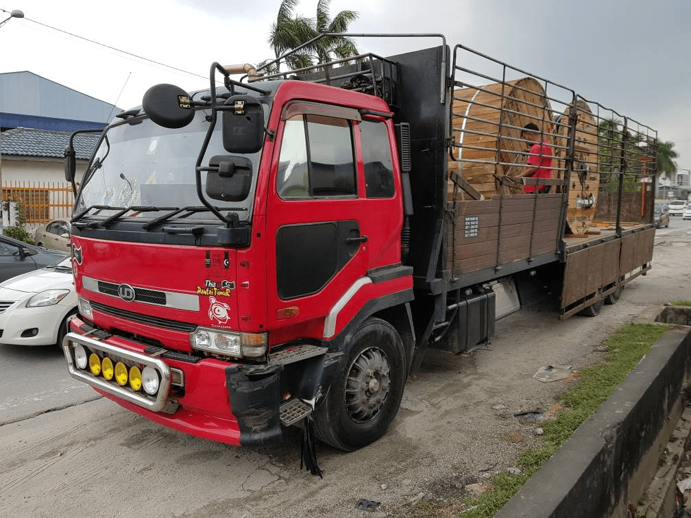 Red truck carrying large wooden spools on a road.