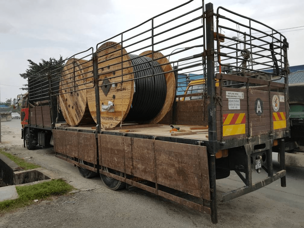 Truck carrying two large wooden cable spools.