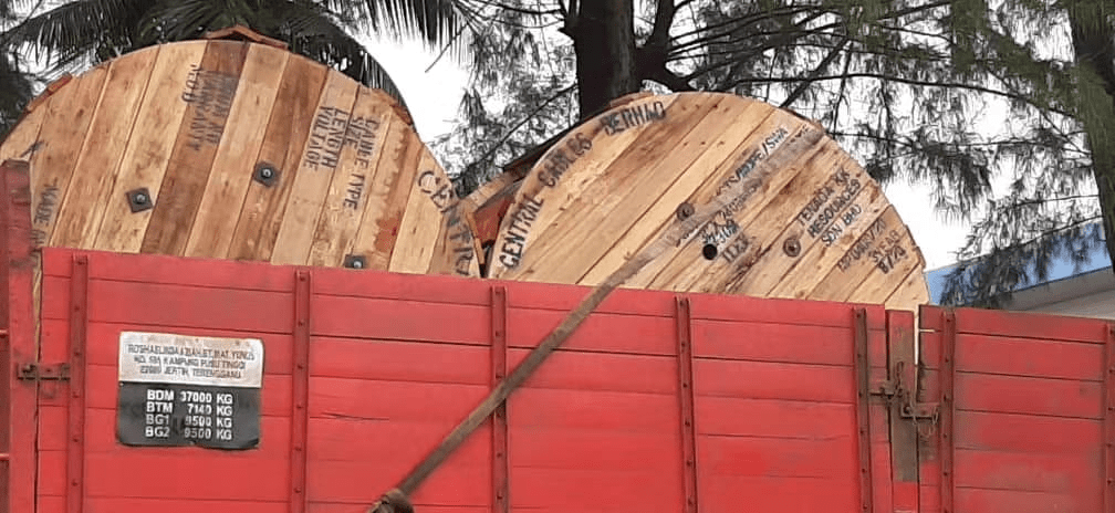 Two large wooden cable spools loaded on a red truck.