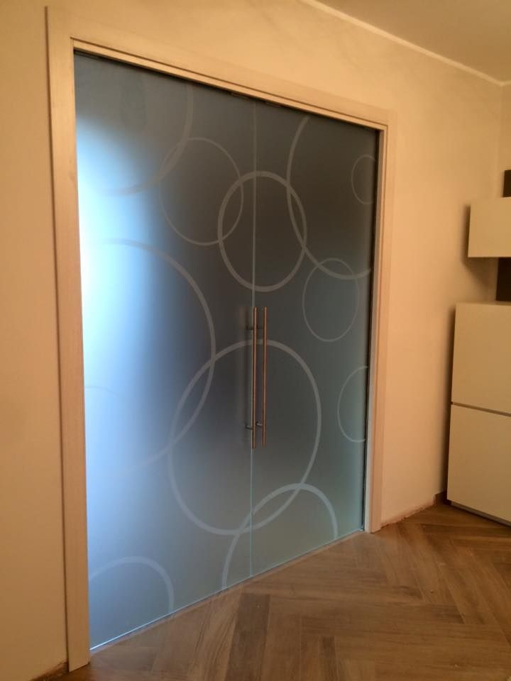 Porta scorrevole in vetro con motivo a cerchi smerigliati, inserita in una cornice beige chiaro, per interni.