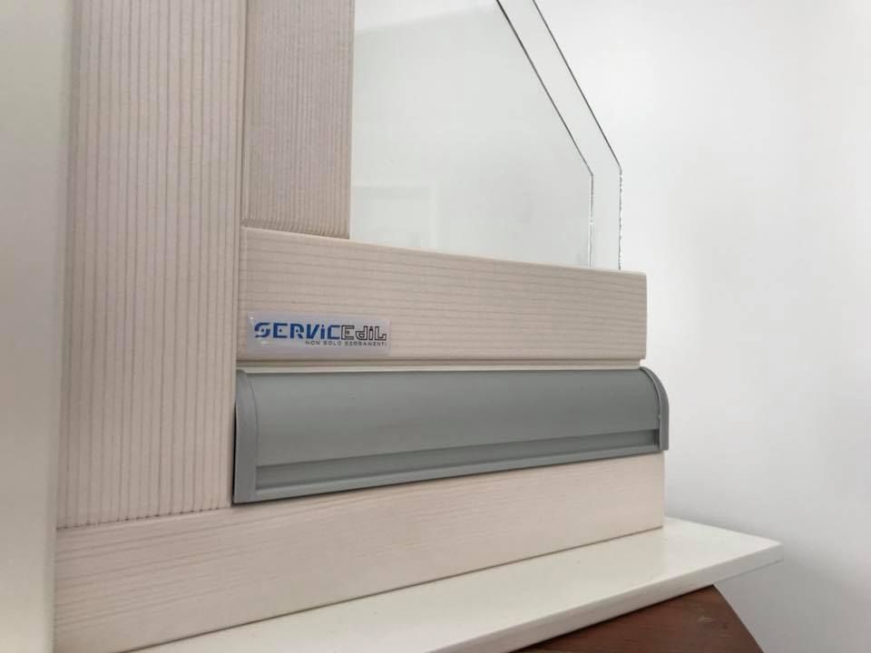 Close-up of a window frame with a gray ventilation system, and a clear glass pane.