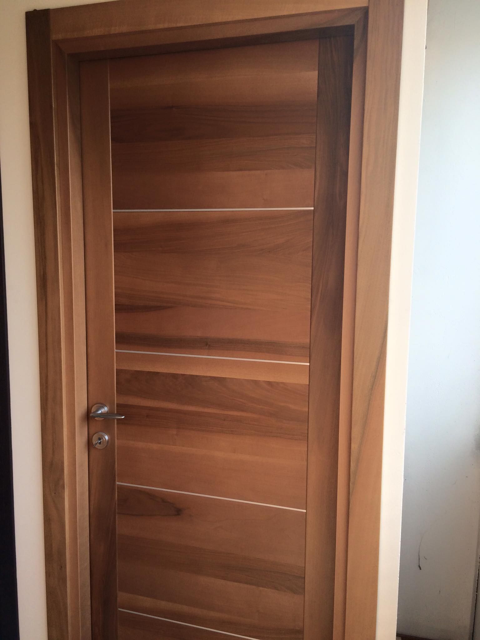 Porta in legno con venature orizzontali e verticali. Maniglia in nichel spazzolato.