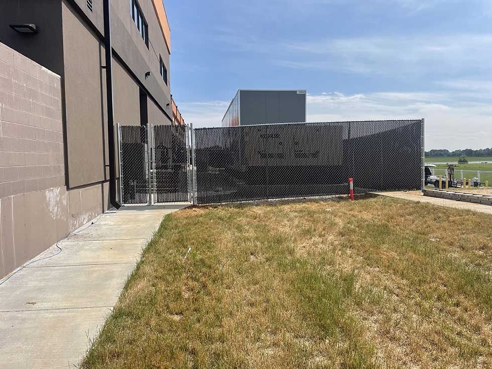 Exterior view of a building with a fenced-in area and dry grass. Blue sky overhead.