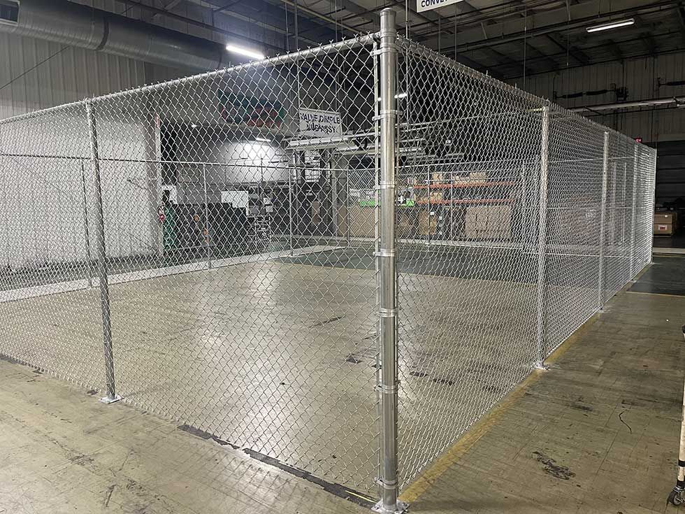 Chain-link fence enclosure within a warehouse setting.