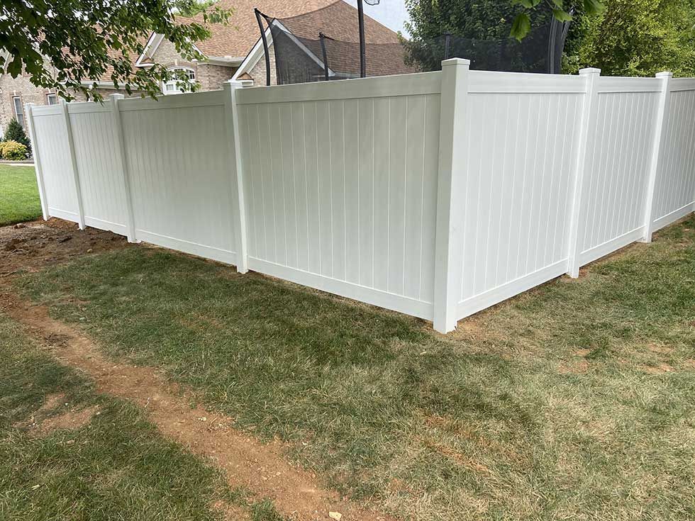White vinyl privacy fence in a grassy yard.