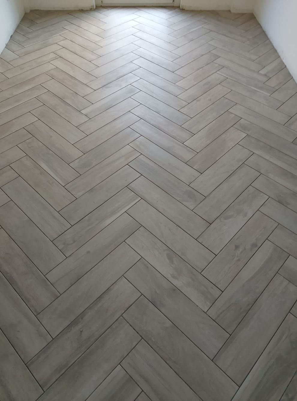 Una stanza con pavimento effetto legno grigio chiaro posato a spina di pesce.