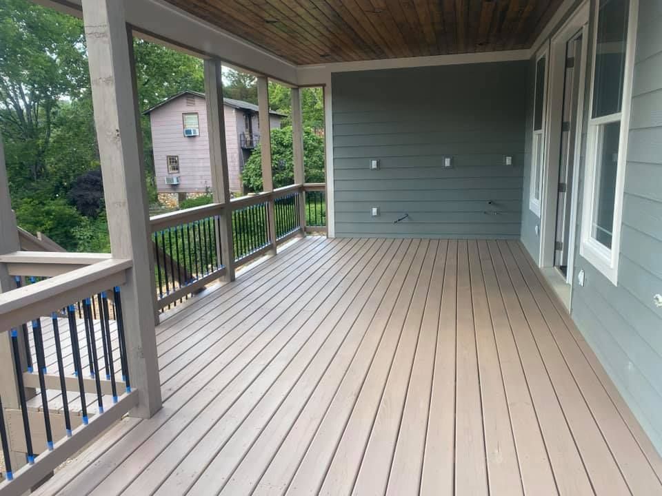 A large deck with a screened in porch and a house in the background