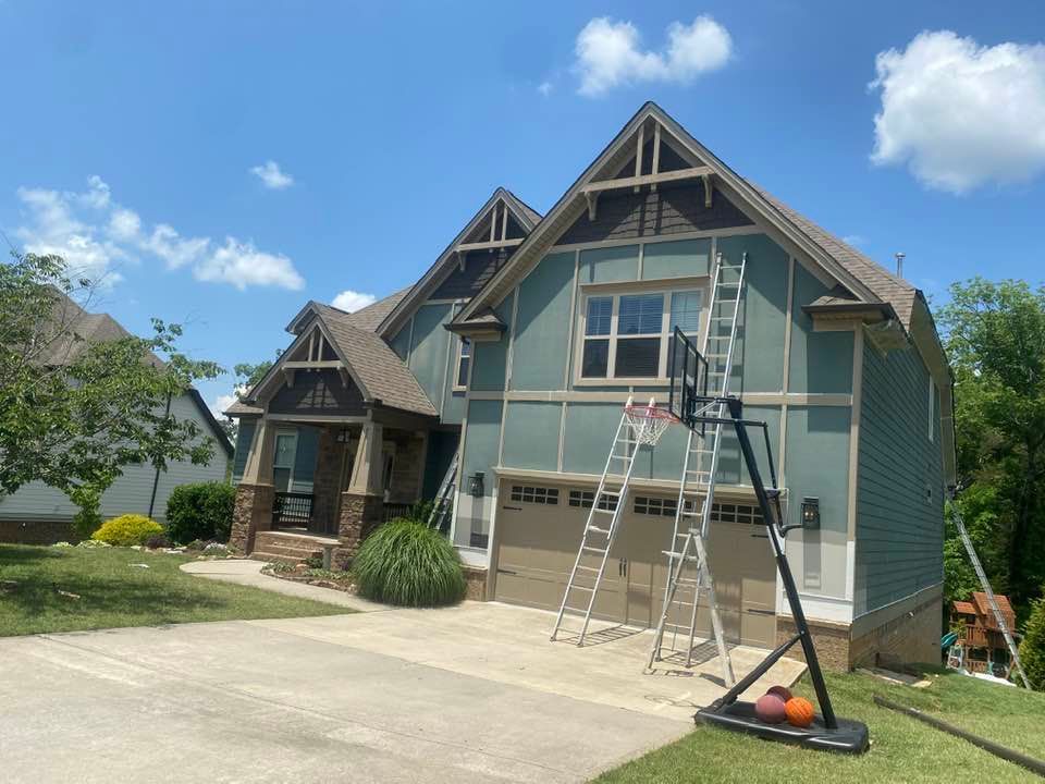 A house is being painted with a ladder and a basketball hoop in front of it.