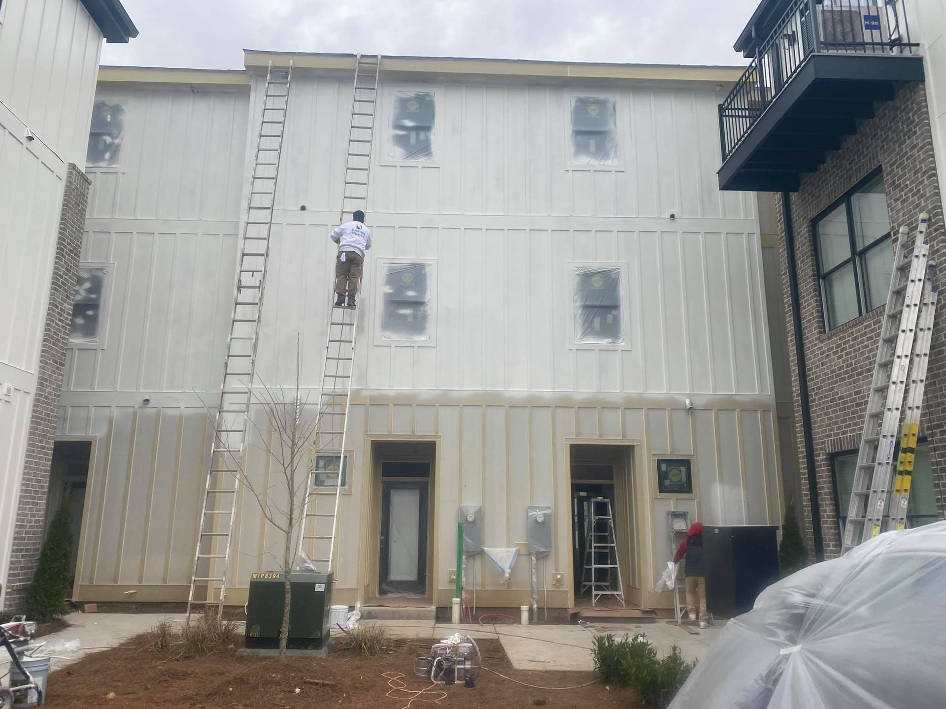 A man on a ladder is painting the side of a building.