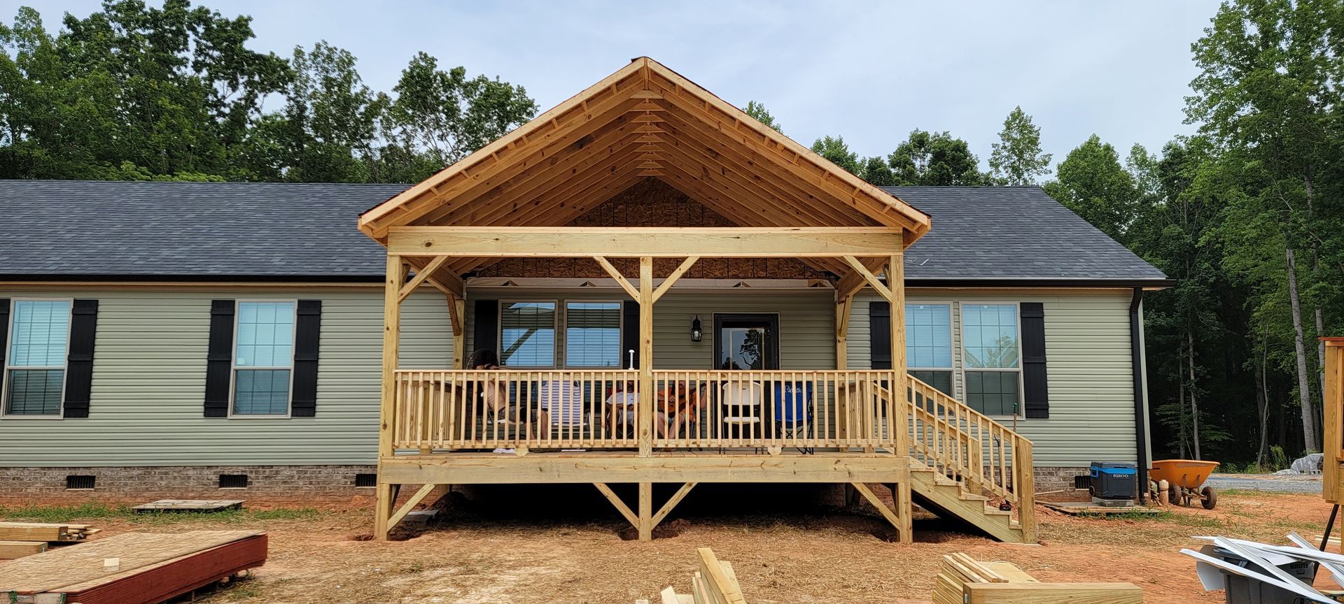 A house with a wooden porch and stairs is being built.