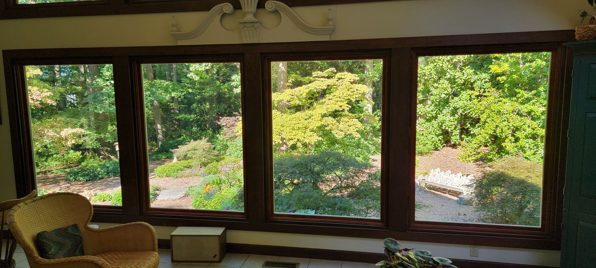 A living room with a lot of windows and a wicker chair.