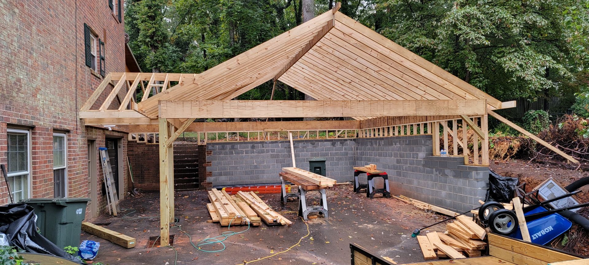 A wooden structure is being built in the backyard of a house.