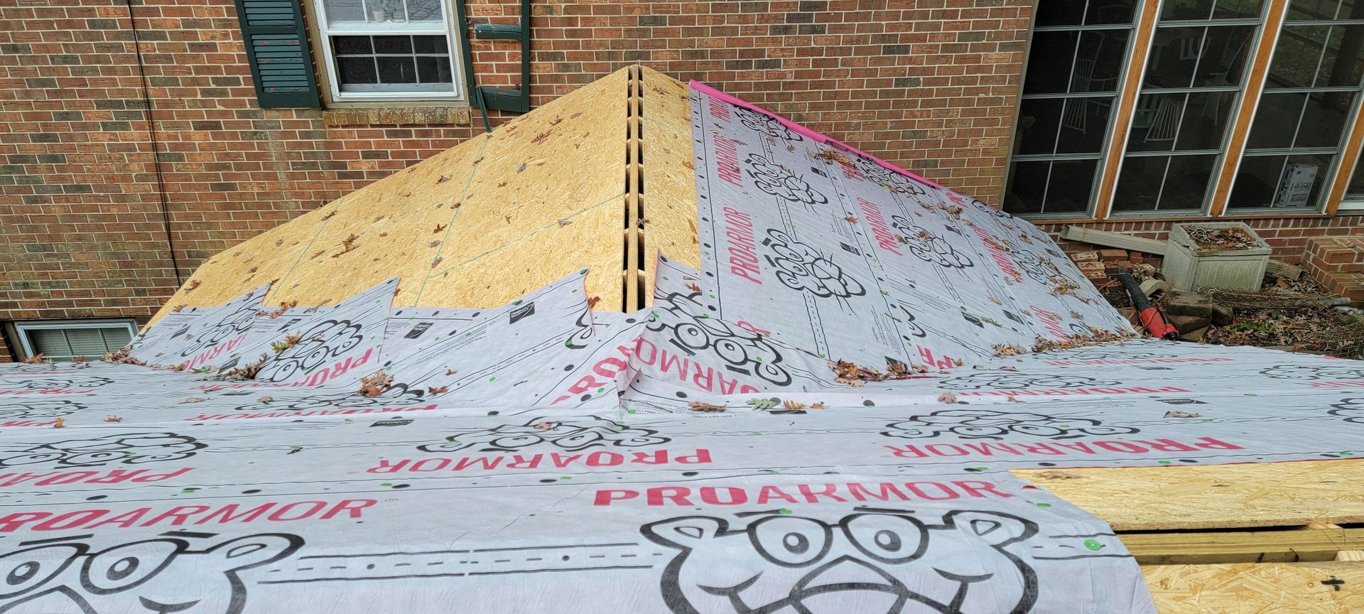 A roof is being built on top of a brick house.