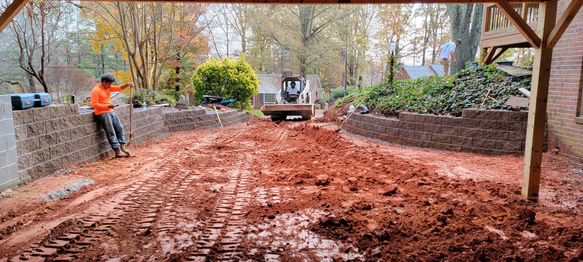 A man is standing next to a bulldozer in a muddy driveway.