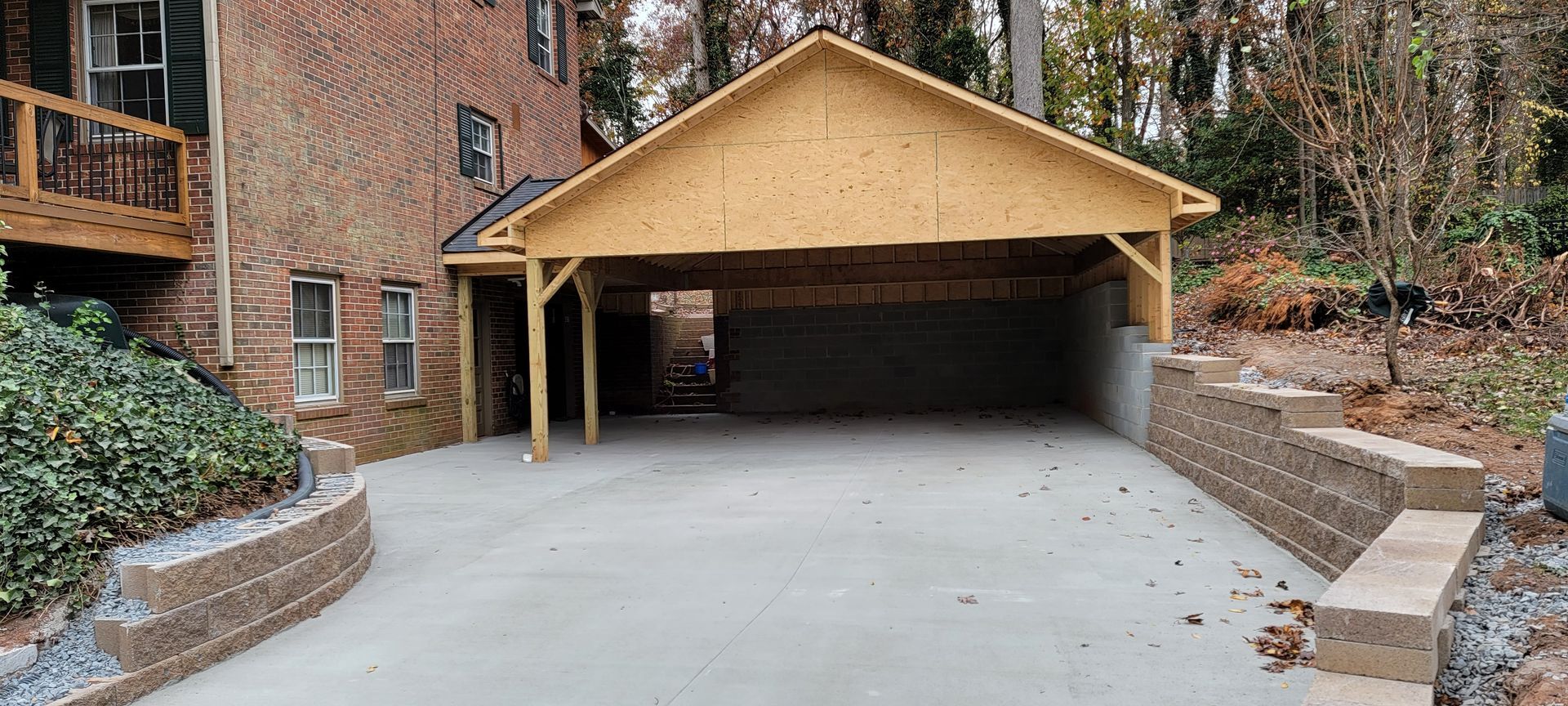A carport is being built in front of a brick house.